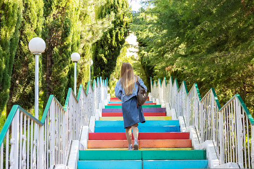 A woman climbs up colored, multi-colored stairs. Concrete colored steps