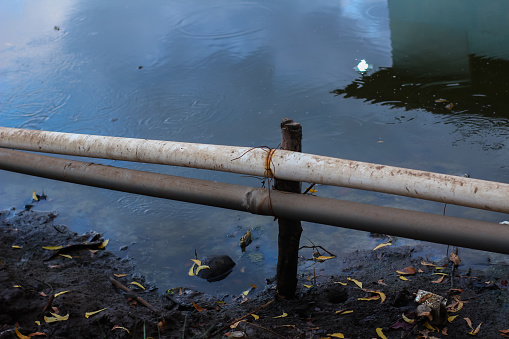 The pipe is supported over the river and is supported by wood