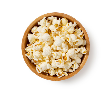 Popcorn in a wooden bowl placed on a white background. View from above.