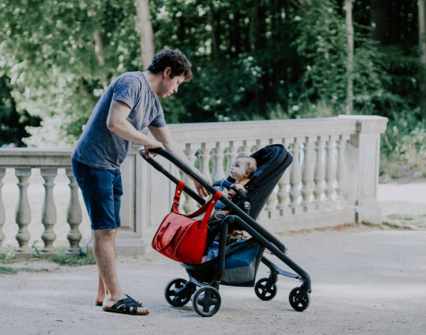 istock Caucasian young male dad pulls his hand to a little daughter sitting in a stroller 1422067335