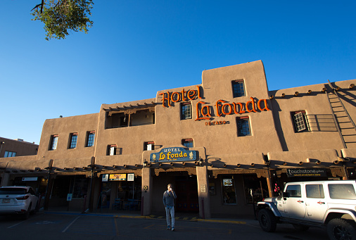 Taos, NM: A tourist walks from the historic La Fonda Hotel in early morning. La Fonda is located on the historic Taos Plaza.