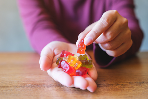 Closeup image of a woman holding and picking up a jelly gummy bear