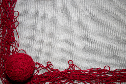 top view of crocheted gray background with red yarn border with a place for text, for yarn and crafting hobby related needs with copy space with ball of yarn