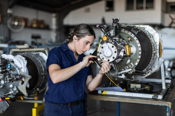 real life young female aircraft engineer apprentice at work - machine part imagens e fotografias de stock