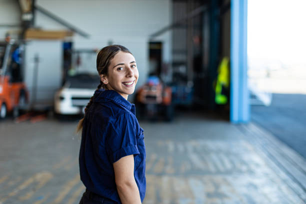 Portrait of smiling young female mechanic with hands on hips in auto repair shop