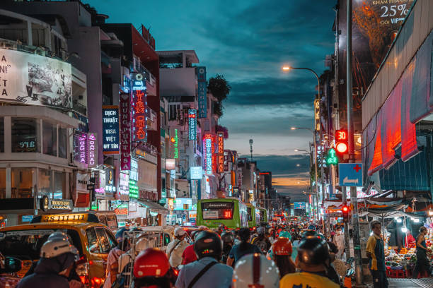 Rush hour, busy traffic jam during sunset and colorful perspective of Hai Ba Trung St with numerous hotel, bar and shop sign boards, crowded with people, motorbikes stock photo