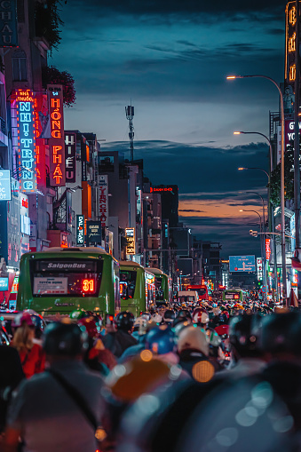 Ho Chi Minh city, Vietnam - 08 Sep 2022: Busy traffic jam during sunset and colorful perspective of Hai Ba Trung St with numerous hotel, bar and shop sign boards, crowded with people, motorbikes