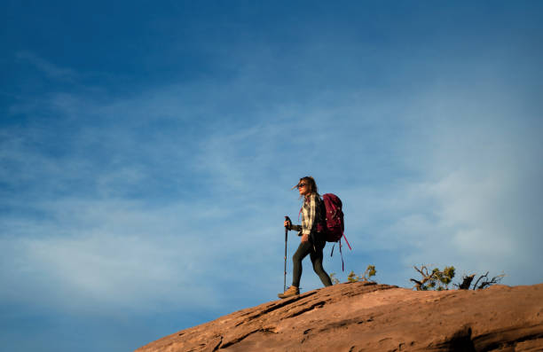 woman walking on edge of cliff at red rock canyon shot from behind