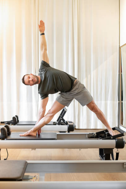 istock Man performing triangle pose on pilates reformer bed 1422098139