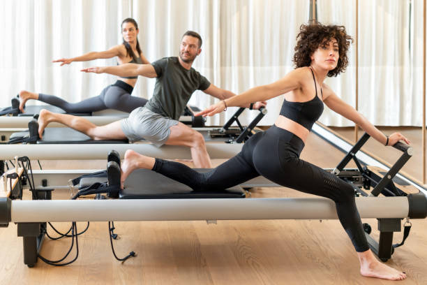 People stretching on pilates reformers stock photo
