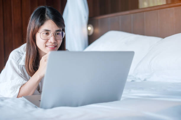 istock Happy woman using laptop for work, female meeting  online by computer notebook on bed. technology, network, work from home, lifestyle and digital communication concept 1422103979