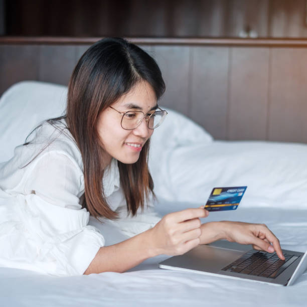 istock woman using computer laptop and credit card for online shopping while making order on bed in morning at home. technology, ecommerce, digital banking online payment and apartment living concept 1422104004