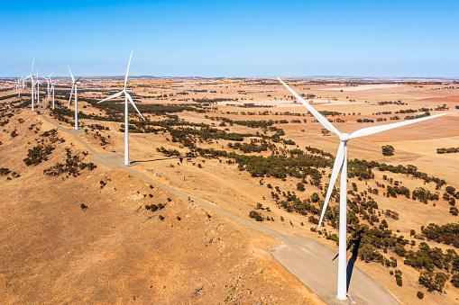 Aerial view of a Wind Farm with blue sky in an open paddock.