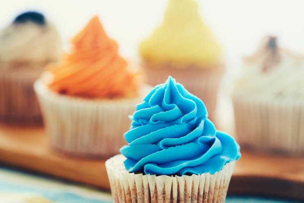Four cupcakes decorated with colorful cream on a table.