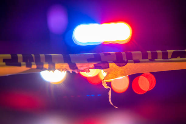 Generic police lights and crime scene tape A defocused police car sits behind crime scene tape with flashing lights at night. generic description stock pictures, royalty-free photos & images