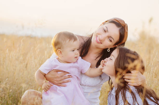 istock happy mom with two little daughters on summer field at sunset 1422111949