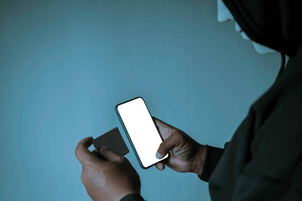 istock An anonymous masked hacker is using a smartphone to penetrate credit card financial information. Hacking and malware concept. 1422112014