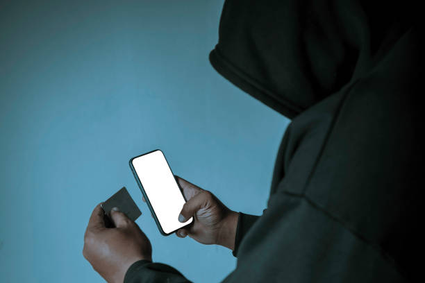 istock An anonymous masked hacker is using a smartphone to penetrate credit card financial information. Hacking and malware concept. 1422112031