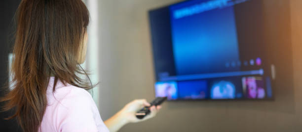 istock woman hand using remote controller for adjust Smart TV inside the modern room at home 1422112804