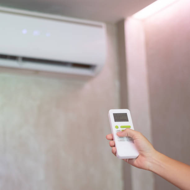 istock hand using remote controller for adjust Air conditioner inside the room of office or home 1422112845