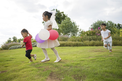 Asian kids playing with balloons in the grass