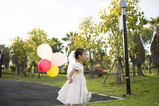 Cute little girl playing with balloons in the grass