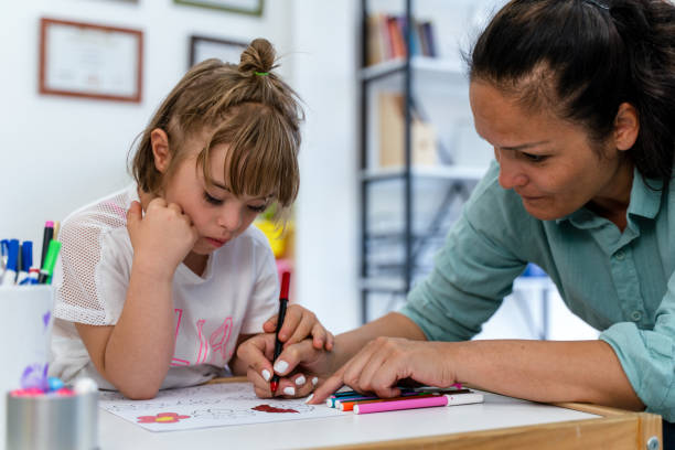 istock female teacher guiding her student with down syndrome drawing in classroom 1422120563