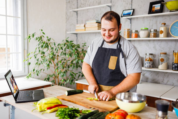 glücklicher mann, der gesundes essen in der küche kocht - fett nährstoff stock-fotos und bilder