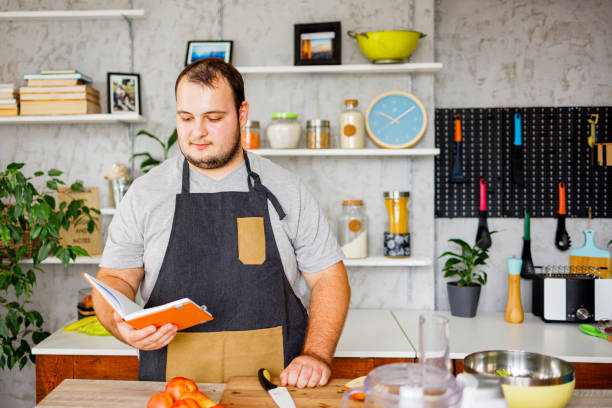 istock Overweight man reading recipe from notebook while preparing healthy meal 1422122386