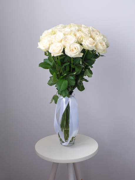 beau bouquet de roses blanches en fleurs dans un vase en verre sur table ronde - hybrid tea rose photos et images de collection