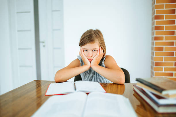 istock Front view looking at the camera sits and misses an elementary school child she must do homework. 1422124048