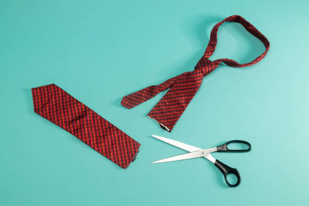 Neckties being cut by a large black scissors.