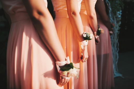 Bridesmaids with flowers stand at the wedding ceremony.