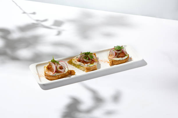 istock Aesthetic composition with tomato bruschetta on white background with harsh shadows. Italian bruschetta with tomatoes and cheese on fine dining in summer. Elegant menu concept. 1422127750