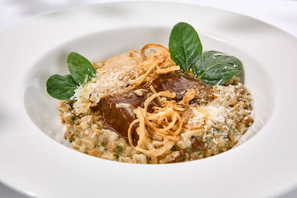 cibo elegante - guance di manzo brasate con grano saraceno e sugo. stufare le guance di vitello con salsa e foglie verdi in piatto bianco con ombre. menu in stile estivo con ombre dure di foglie - pot roast braising steak stew foto e immagini stock