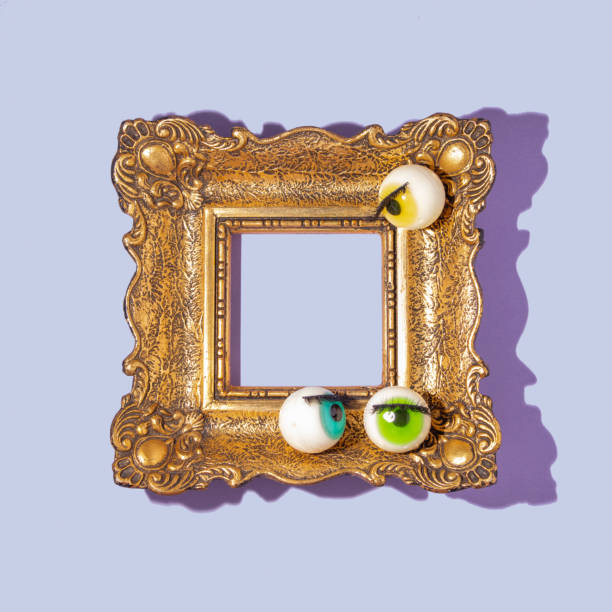istock Creattive layout with eyeball figurines with eyelashs on retro golden painting frame on pastel purple background. Halloween minimal creative concept. Halloween season aesthetic idea. Copy space. 1422131934