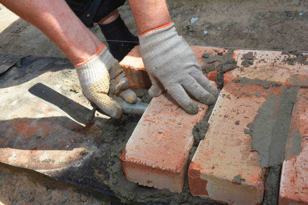 istock Mason bricklaying brick wall on foundation with bitumen barrier. 1422135742