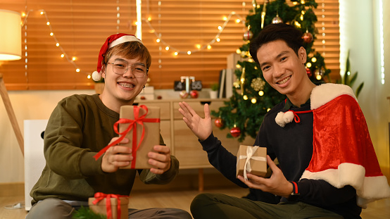 Two happy man holding Christmas present and smiling to camera. Christmas and New year concept.
