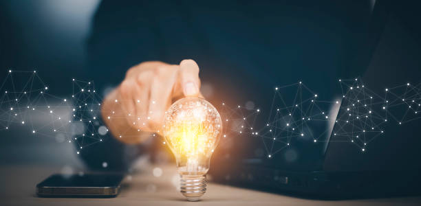 Businessman hand holding light bulb with icons and working on the desk, Creativity and innovation are keys to success.Concept of new idea and innovation with energy and power , working at home, stock photo