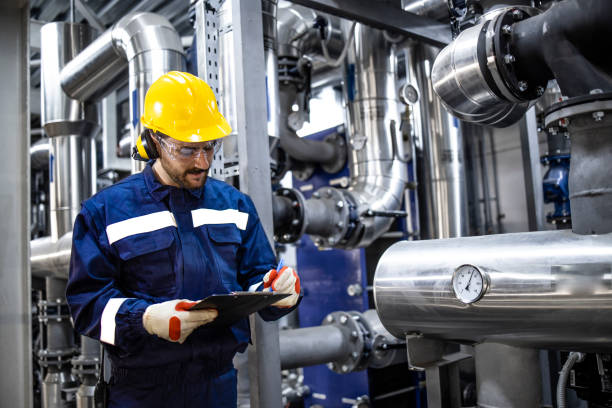 istock Professional worker in protective uniform and hardhat standing by pipes and checking pressure inside gasoline refinery plant. 1422137163