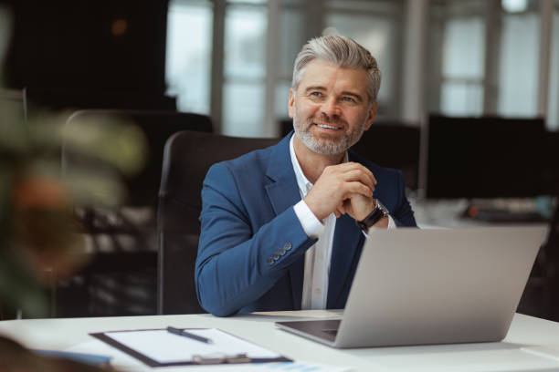 istock Smiling Mature businessman workingon laptop while sitting in modern coworking 1422137792
