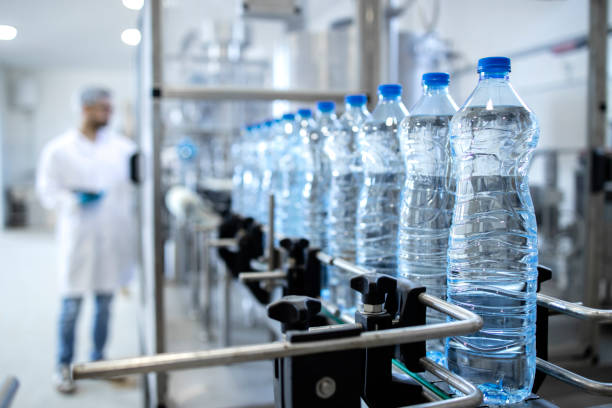 Bottling factory interior and bottles of water ordered in line ready for distribution. Bottling factory interior and bottles of water ordered in line ready for distribution. bottling plant stock pictures, royalty-free photos & images