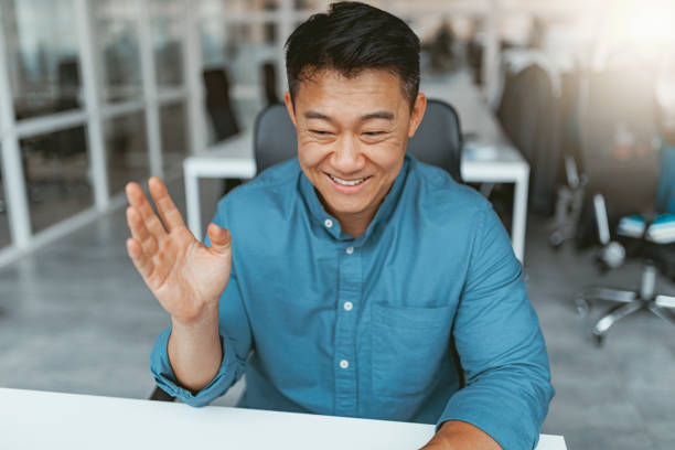 istock Smiling asian businessman talking online with client sitting in office 1422138532