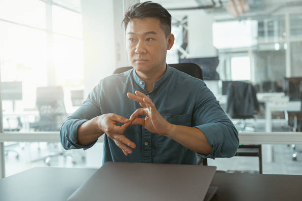 istock Asian businessman using sign language with colleagues and friends while sitting in office 1422139986
