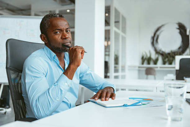 istock Busy African businessman taking notes while working in modern office and looking on camera 1422139988