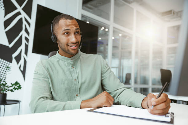 istock Confident African businessman taking notes while talking on phone with client in modern office 1422141049