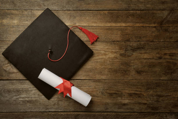 istock Graduation hat and diploma on wooden table, flat lay. Space for text 1422141917
