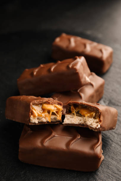 istock Chocolate bars with caramel, nuts and nougat on black table, closeup 1422142166