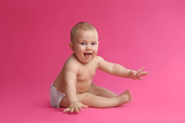 istock Cute baby in dry soft diaper sitting on pink background 1422143686