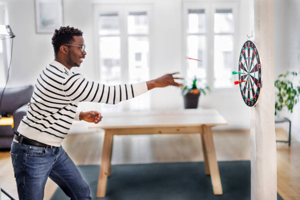 un africano alegre está de fiesta y disfrutando de un juego de dardos. - dartboard photography competition sports and fitness fotografías e imágenes de stock